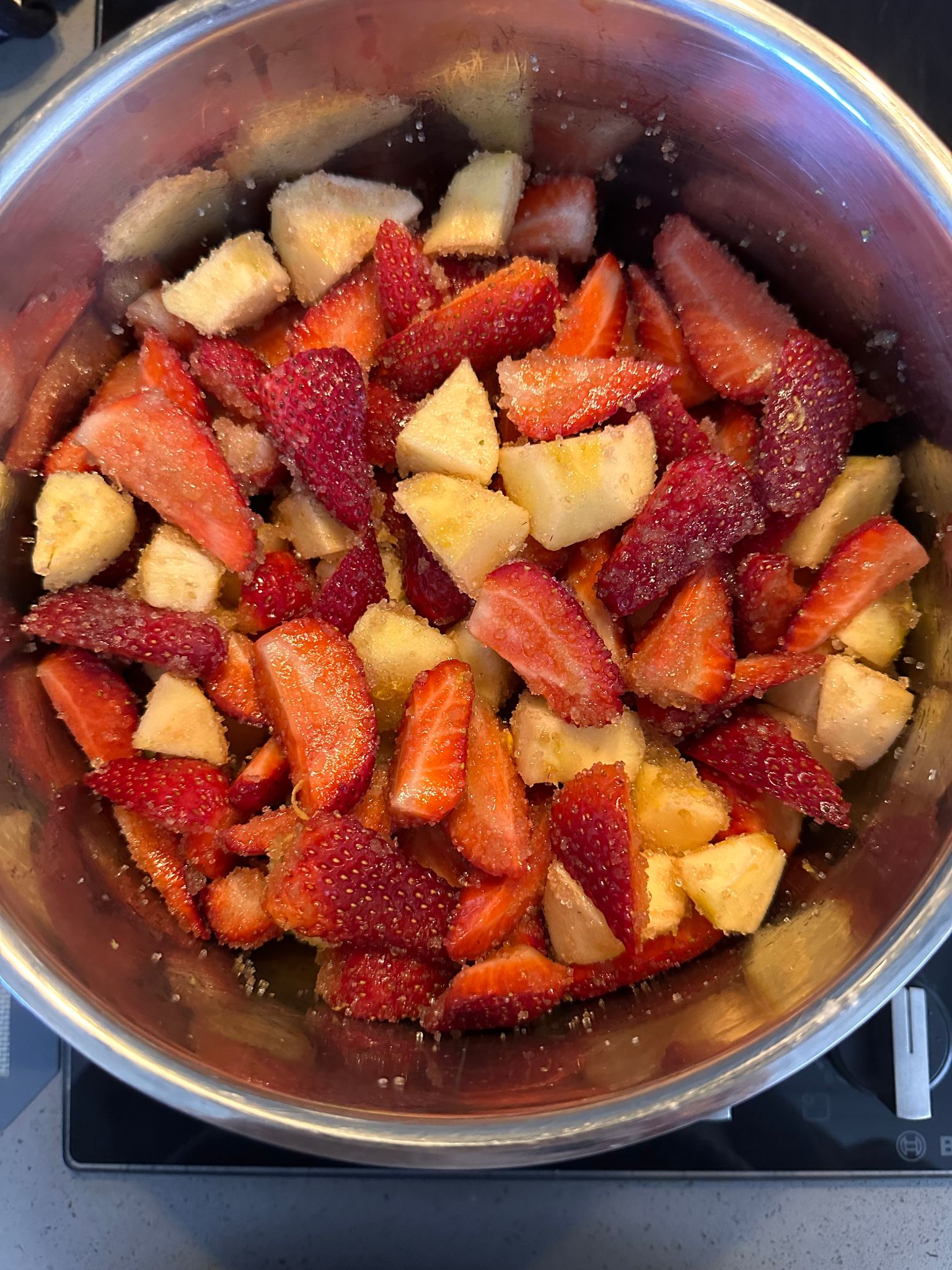 Chopped strawberries and apples with sugar in a pot, ready to start cooking